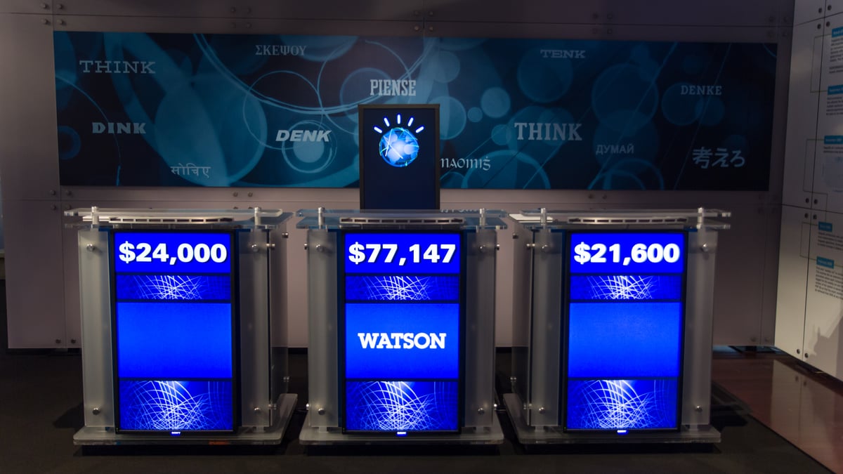 En återskapad Jeopardy-scen med IBM Watsons skärm mellan två andra deltagarplatser.