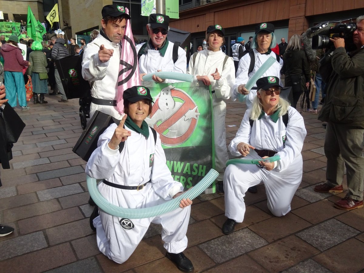 Aktivister kritiserar flygbranschens miljökommunikation. Bilden visar kritikens avsändare, inte i sig att ett visst påstående är vilseledande. Aktivister utklädda till Greenwashbusters vid en demonstration i Glasgow 2021.