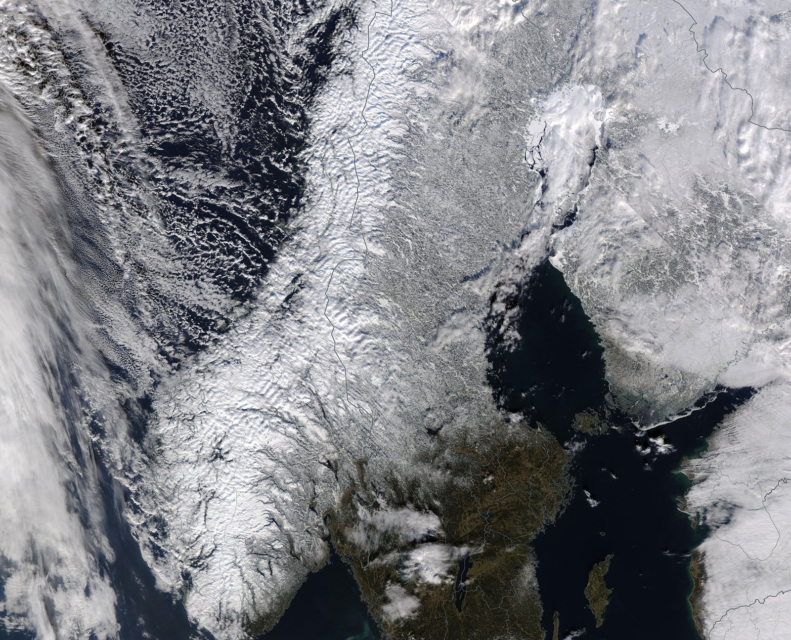 Satellitbild av Skandinavien en vinterdag med snötäckt land och molnsystem över Norska havet och Östersjön.